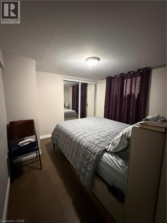 Room featuring dark wood-finish flooring, light neutral walls, and a ceiling-mounted light fixture - 947 Main Street E Unit# 6, Hamilton, ON - Indoor Photo Showing Bedroom