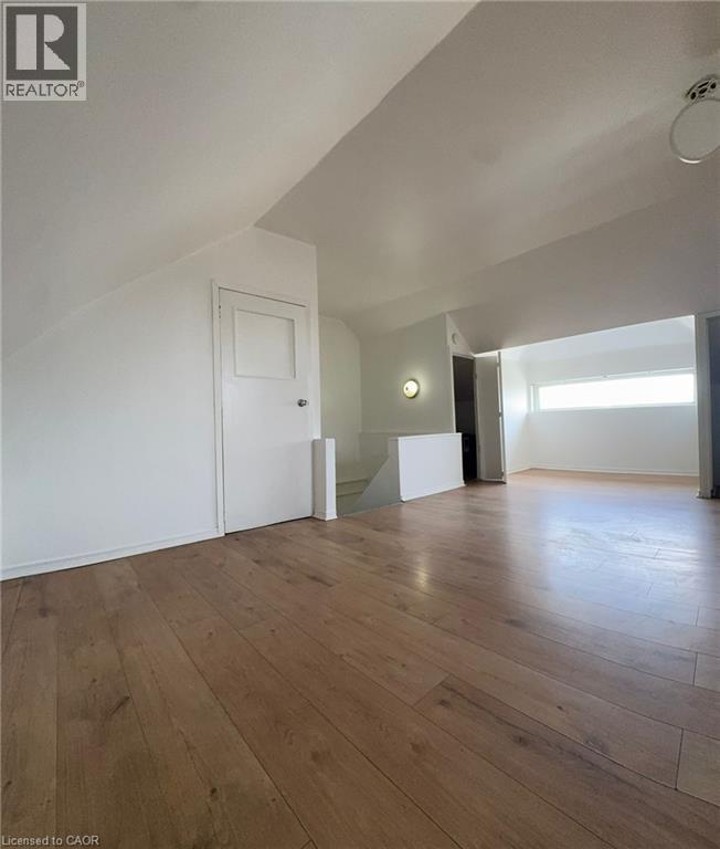 Expansive attic space featuring wood-finish flooring, sloped ceilings, and a horizontal window - 10 Fairleigh Avenue N, Hamilton, ON - Indoor Photo Showing Other Room