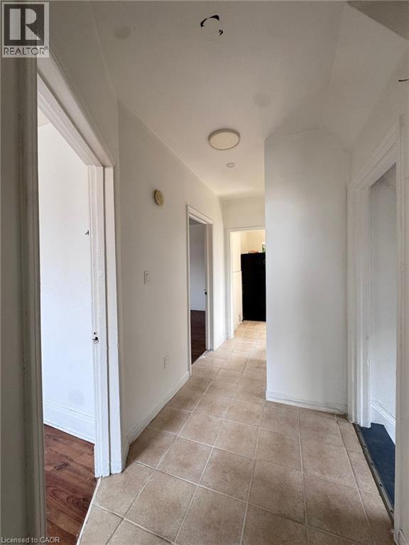 Hallway with neutral-toned square tile flooring, white walls, and multiple doorways - 10 Fairleigh Avenue N, Hamilton, ON - Indoor Photo Showing Other Room