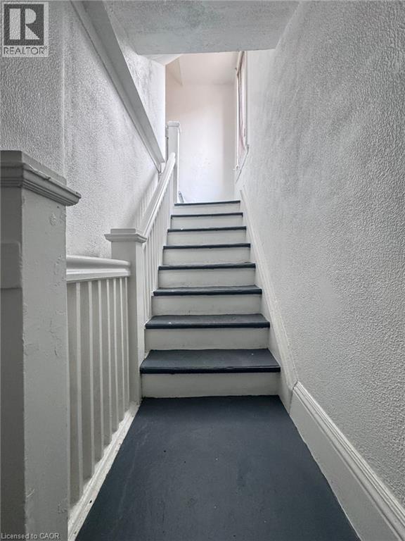 Stairwell featuring painted white risers and dark treads, white balusters, and textured wall finishes - 10 Fairleigh Avenue N, Hamilton, ON - Photo Showing Other Room