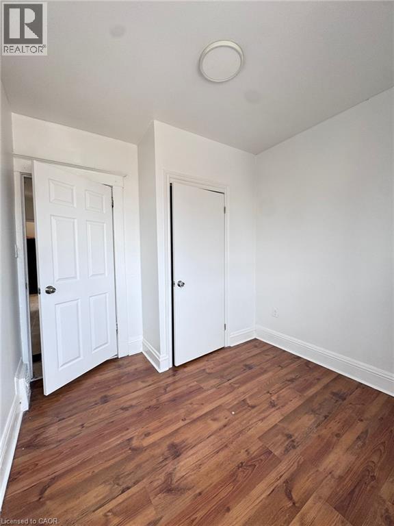 Room featuring wood-finish flooring, white walls, white trim, and a ceiling light fixture - 10 Fairleigh Avenue N, Hamilton, ON - Indoor Photo Showing Other Room