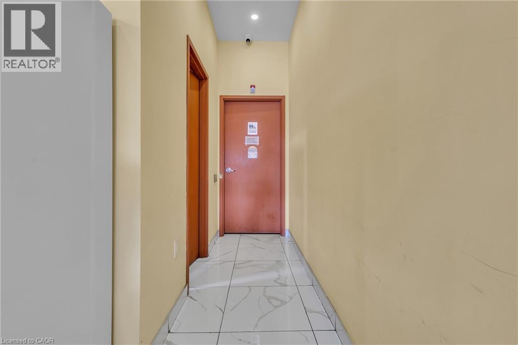 Hallway with light beige walls and white-patterned floor tiles - 5 Manitou Drive Unit# 106B, Kitchener, ON