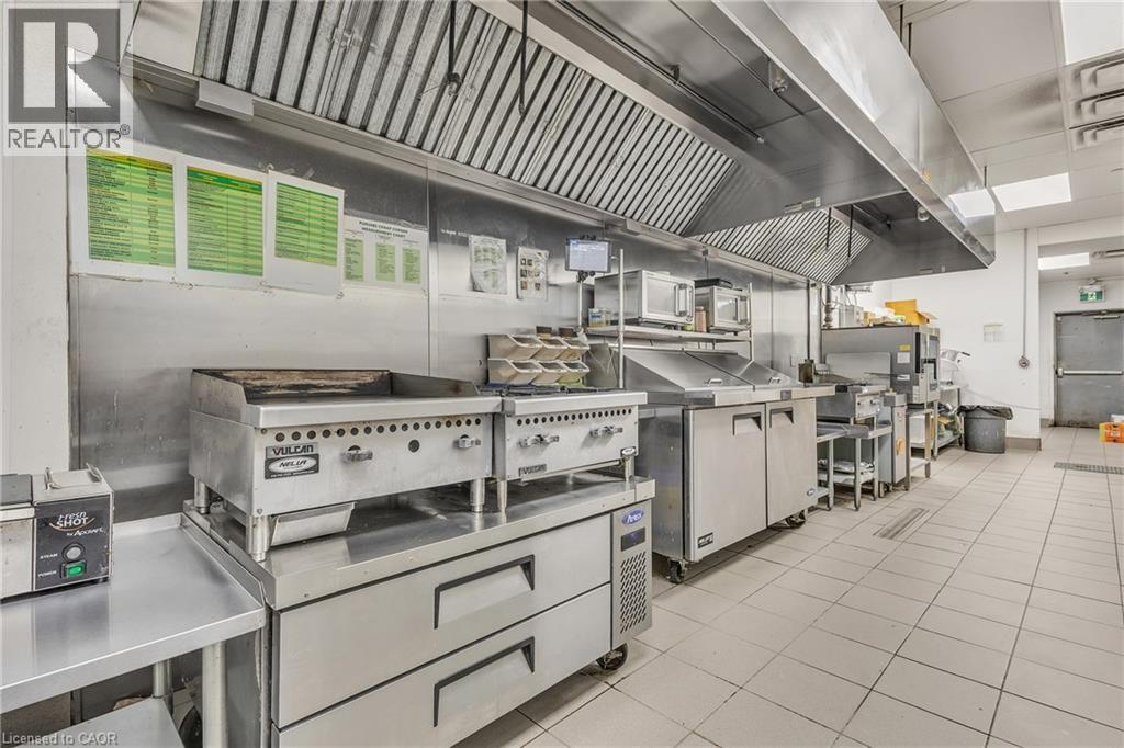 Commercial kitchen featuring stainless steel equipment and extensive counter space - 5 Manitou Drive Unit# 106B, Kitchener, ON
