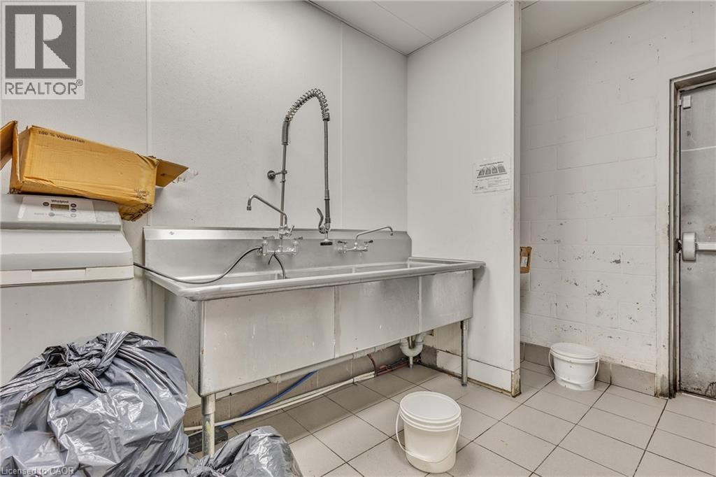 Stainless steel commercial sink with multiple faucet fixtures, featuring a pull-down sprayer and durable construction - 5 Manitou Drive Unit# 106B, Kitchener, ON