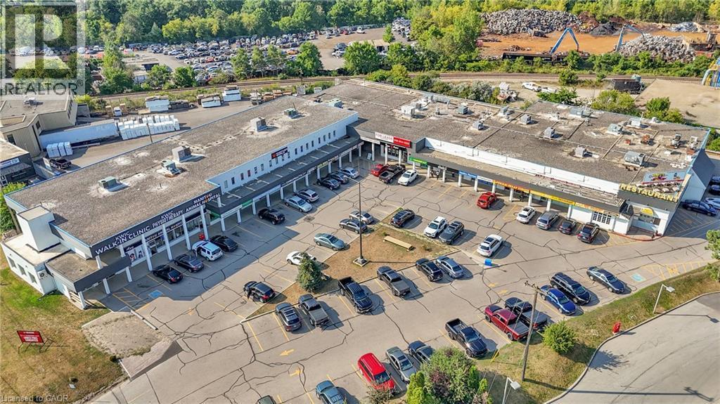 Commercial plaza featuring multiple retail units, dedicated parking, and a prominent corner location - 5 Manitou Drive Unit# 106B, Kitchener, ON