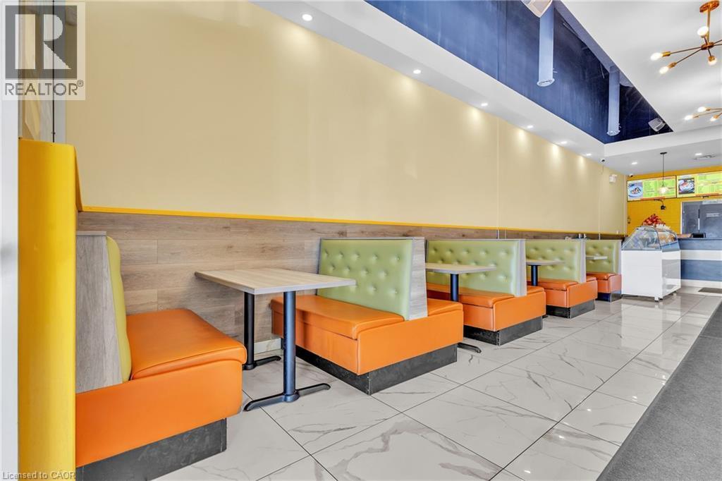 Commercial space featuring a row of booth seating, wood-finish wall paneling, and a high ceiling with recessed lighting - 5 Manitou Drive Unit# 106B, Kitchener, ON