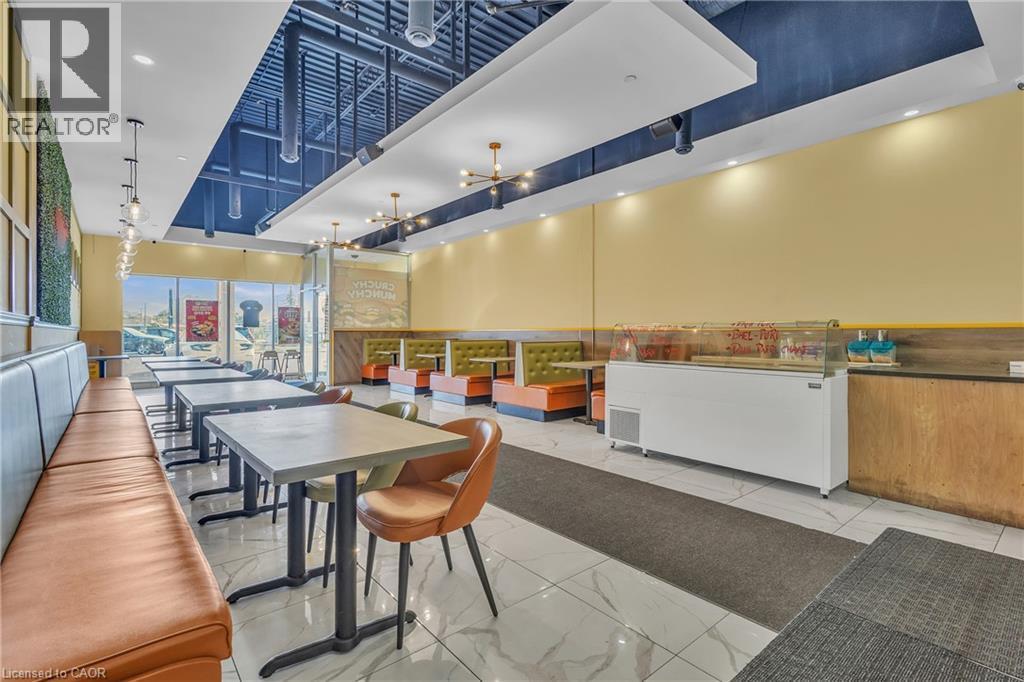 Spacious commercial interior featuring a mix of booth and table seating, large storefront windows, and modern light fixtures - 5 Manitou Drive Unit# 106B, Kitchener, ON