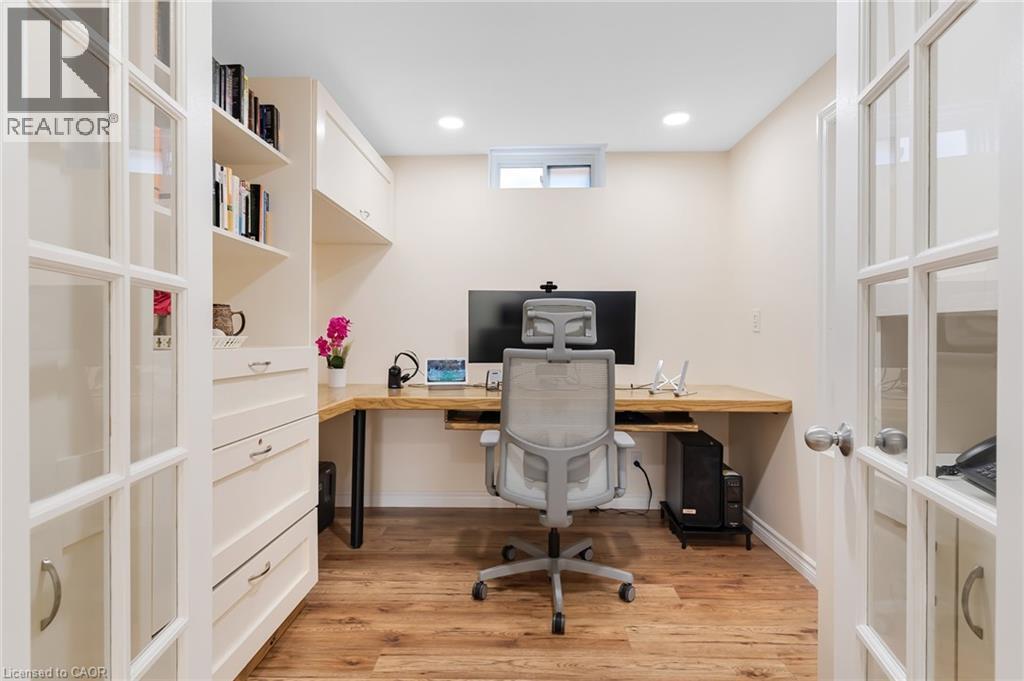 Dedicated office space featuring French doors, wood-finish flooring, built-in cabinetry, recessed lighting, and a built-in L-shaped desk - 42 Handorf Drive, Cambridge, ON - Indoor Photo Showing Office