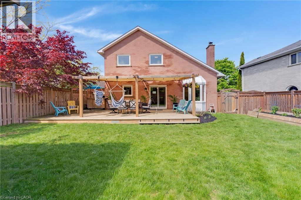 Expansive backyard featuring a large wood deck with a pergola, brick exterior, bay window, and a manicured lawn - 42 Handorf Drive, Cambridge, ON - Outdoor With Deck Patio Veranda