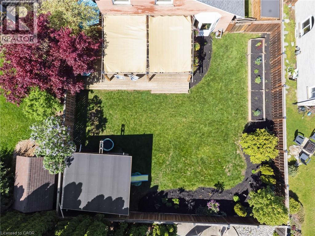 Expansive backyard featuring a large green lawn, a multi-level wood deck with retractable awnings, and a dedicated storage shed - 42 Handorf Drive, Cambridge, ON - Outdoor
