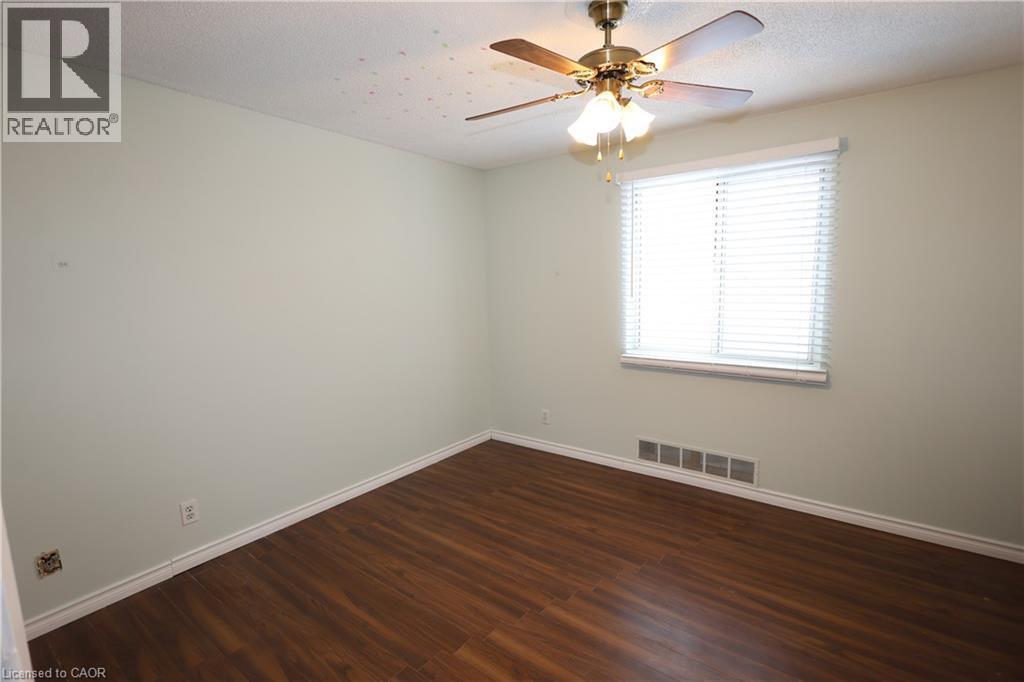 Room featuring wood-finish flooring, a ceiling fan with integrated lighting, and a window equipped with horizontal blinds - 67 Valleyview Road Unit# 58, Kitchener, ON - Indoor Photo Showing Other Room