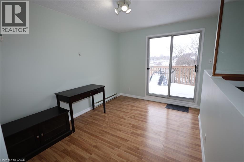 Light wood-finish flooring complements the pastel wall color in this open living space featuring a sliding glass door providing access to an exterior deck - 67 Valleyview Road Unit# 58, Kitchener, ON - Indoor Photo Showing Other Room