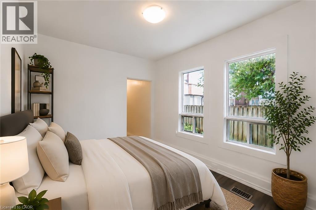 Bedroom featuring two bright windows, dark wood-finish flooring, white baseboards, and a flush-mount ceiling light - 87 Lancaster Street W, Kitchener, ON - Indoor Photo Showing Bedroom