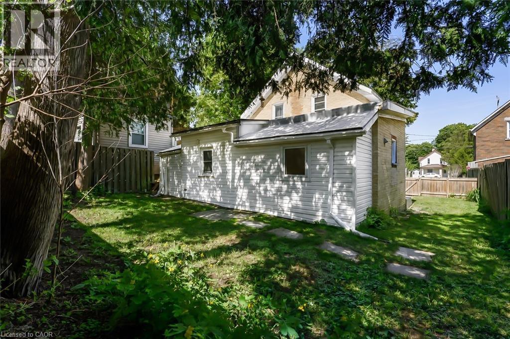 Expansive backyard featuring a grass lawn, mature trees, and a wooden privacy fence - 87 Lancaster Street W, Kitchener, ON - Outdoor