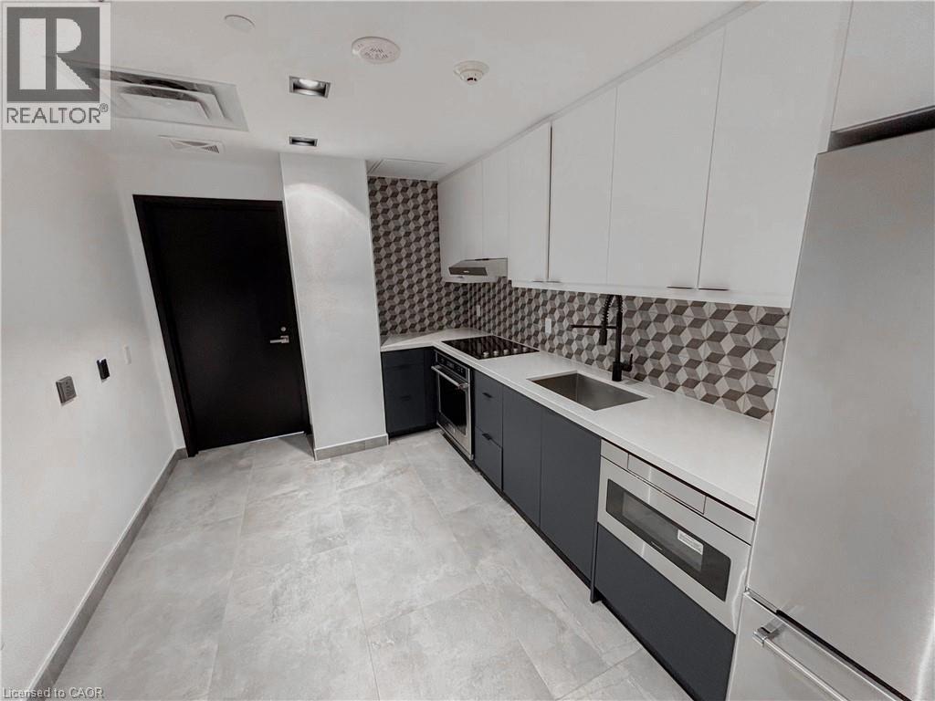 Contemporary kitchen featuring light gray tile flooring and a geometric tiled backsplash - 15 Wellington Street S Unit# 1909, Kitchener, ON - Indoor Photo Showing Kitchen