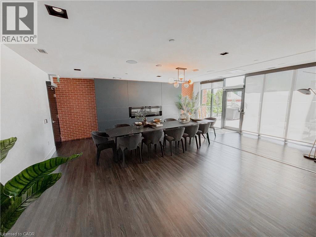 Spacious room featuring wood-finish flooring, a contemporary linear fireplace, and a brick accent wall - 15 Wellington Street S Unit# 1909, Kitchener, ON - Indoor