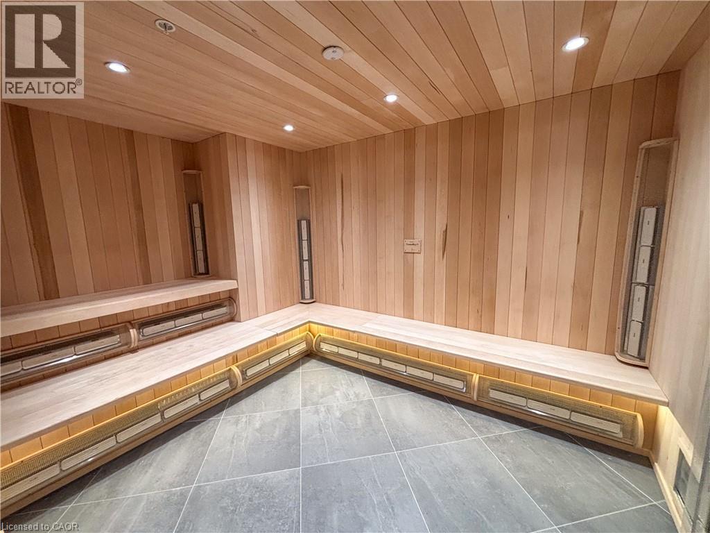 Custom-built sauna with light wood paneling, multi-level bench seating, built-in heaters, recessed ceiling lighting, and large format tile flooring - 15 Wellington Street S Unit# 1909, Kitchener, ON - Indoor Photo Showing Other Room