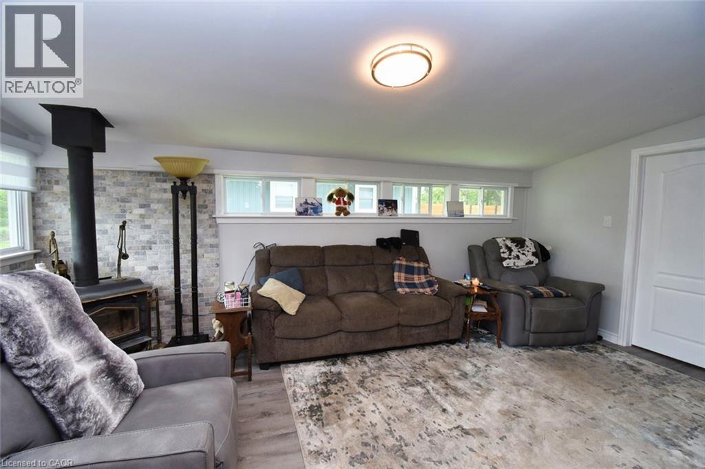 Living area featuring a wood-burning stove with a stone-finish accent wall - 5 Ralph Street, Turkey Point, ON - Indoor Photo Showing Living Room