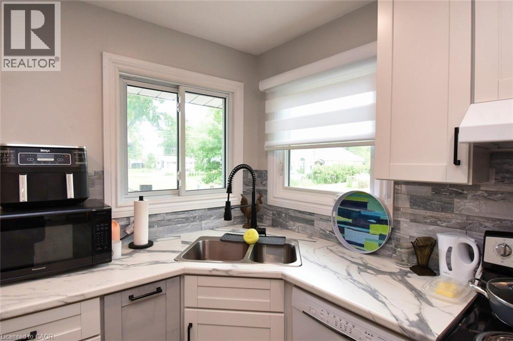 Corner kitchen sink with a gooseneck faucet, set within a countertop featuring a gray veining pattern - 5 Ralph Street, Turkey Point, ON - Indoor Photo Showing Kitchen