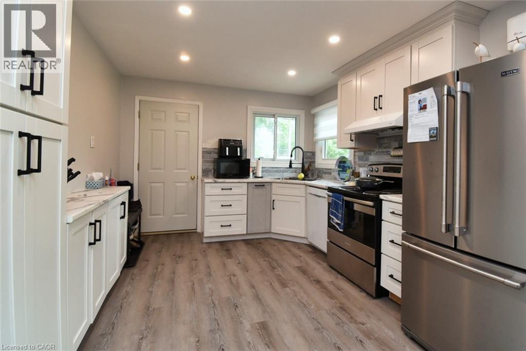 Kitchen featuring wood-finish flooring, white cabinetry with dark hardware, stainless steel appliances, and recessed lighting - 5 Ralph Street, Turkey Point, ON - Indoor Photo Showing Kitchen