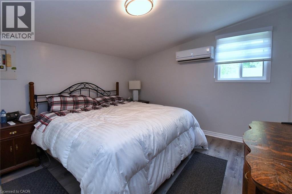 Bedroom featuring light gray walls, wood-finish flooring, and a flush-mount ceiling light - 5 Ralph Street, Turkey Point, ON - Indoor Photo Showing Bedroom