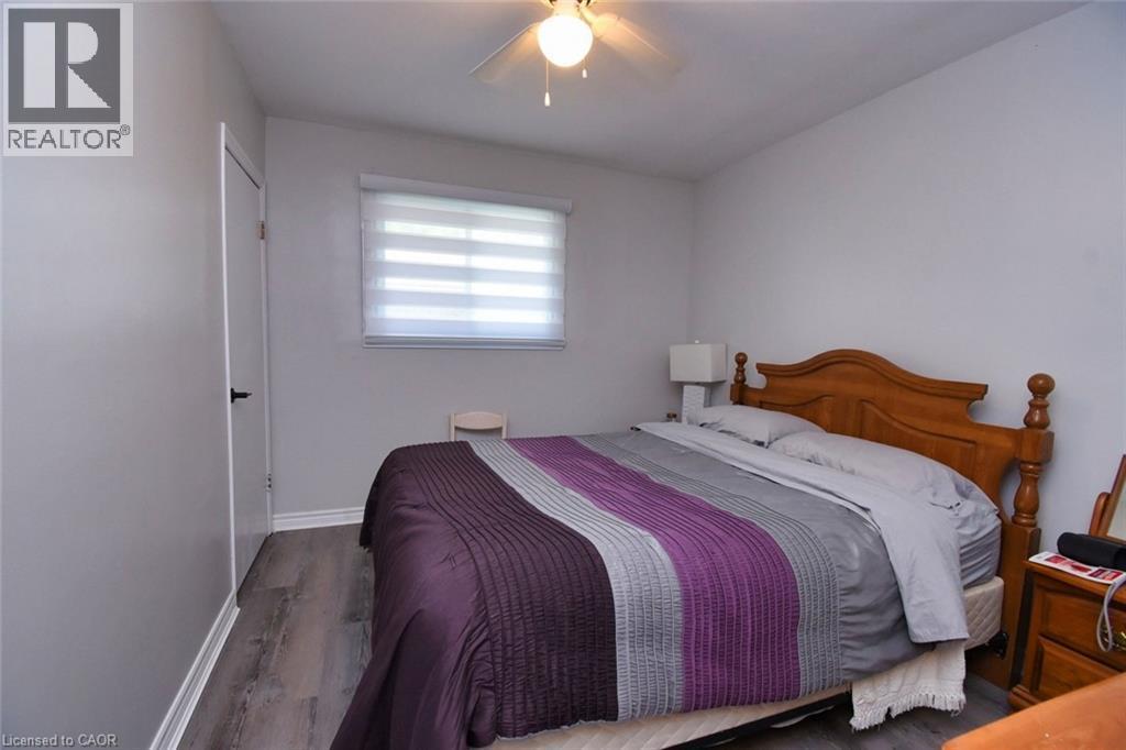 Neutral gray walls complement the wood-finish flooring in this room - 5 Ralph Street, Turkey Point, ON - Indoor Photo Showing Bedroom