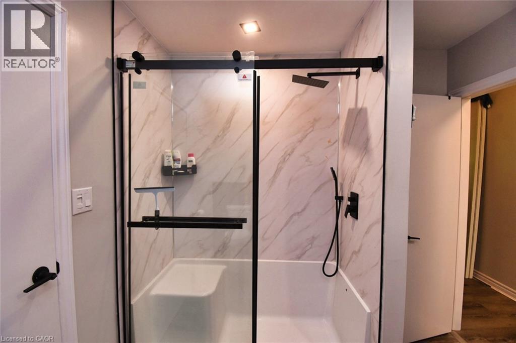 Walk-in shower with clear glass barn-door style enclosure and matte black hardware - 5 Ralph Street, Turkey Point, ON - Indoor Photo Showing Bathroom