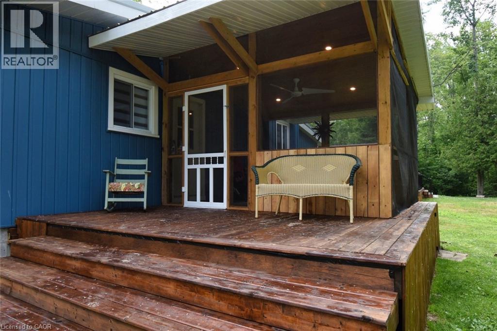 Expansive outdoor wood deck with multiple steps, extending to a screened porch featuring natural wood framing, recessed lighting, and a ceiling fan - 5 Ralph Street, Turkey Point, ON - Outdoor With Deck Patio Veranda With Exterior