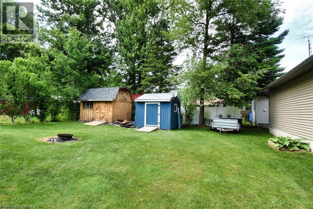 Expansive green lawn featuring a built-in fire pit - 5 Ralph Street, Turkey Point, ON - Outdoor