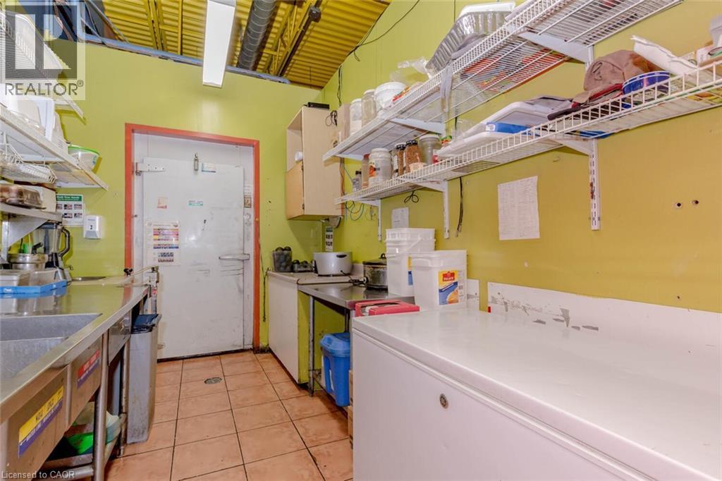 Commercial kitchen space featuring a large walk-in cooler, extensive stainless steel counters, and durable tile flooring - 1035 Brant Street Unit# 1C, Burlington, ON