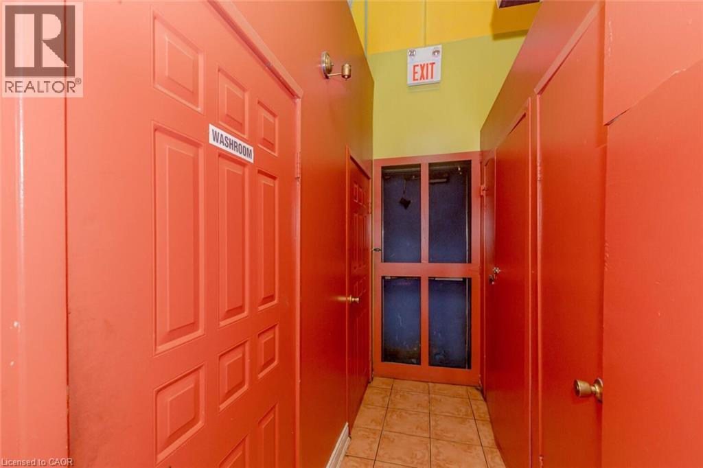 Corridor featuring a tiled floor, painted panel doors, and a wood-framed glass door at the end - 1035 Brant Street Unit# 1C, Burlington, ON
