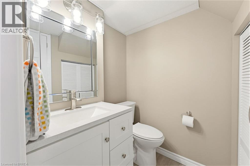 Bathroom vanity with a white countertop and integrated sink, brushed nickel faucet, and a large mirror with overhead lighting - 26 Coachwood Road Unit# 6, Brantford, ON - Indoor Photo Showing Bathroom