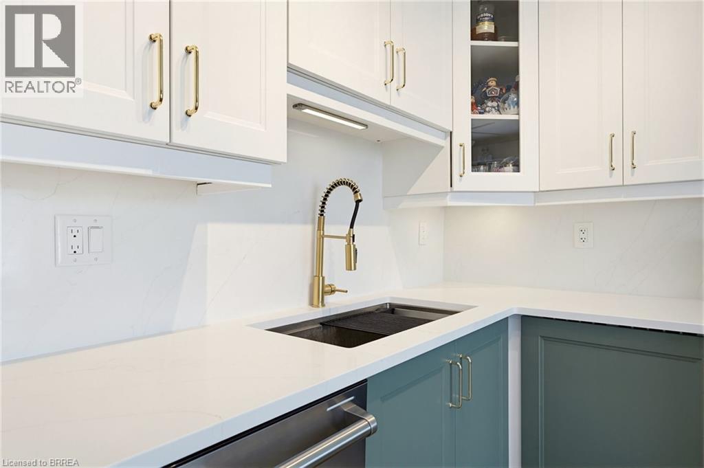 Modern kitchen featuring white upper cabinetry with gold-toned hardware, complementing dark teal lower cabinetry - 26 Coachwood Road Unit# 6, Brantford, ON - Indoor Photo Showing Kitchen With Upgraded Kitchen