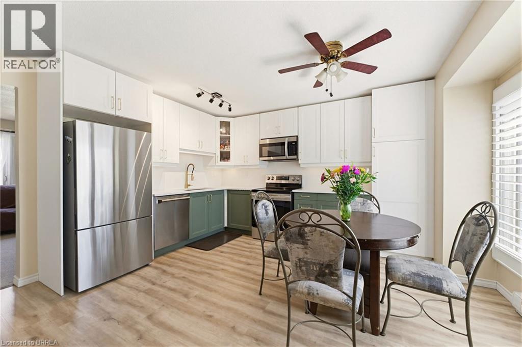 Kitchen featuring light wood-finish flooring, white upper cabinetry, and contrasting green lower cabinetry - 26 Coachwood Road Unit# 6, Brantford, ON - Indoor