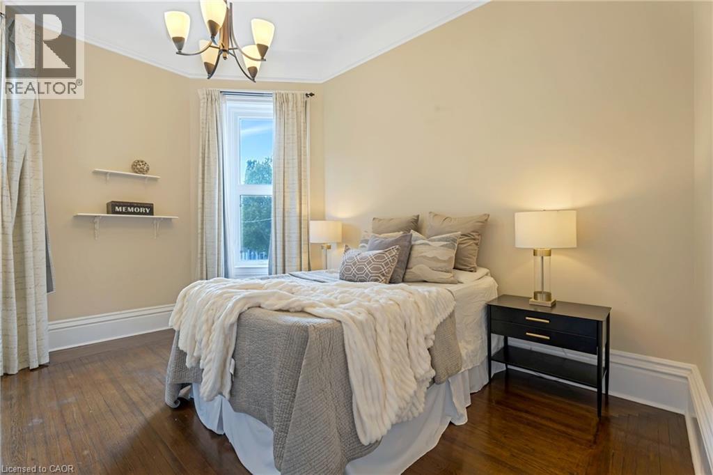 Bedroom with dark wood-style flooring, crown molding, and a chandelier - 46 Herkimer Street Unit# 2, Hamilton, ON - Indoor Photo Showing Bedroom