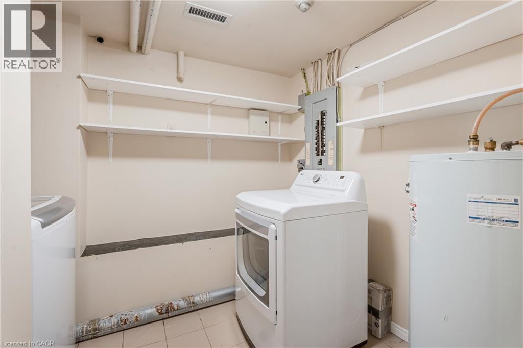 Laundry area with water heater, washer and dryer, light tile patterned flooring, and electric panel - 46 Herkimer Street Unit# 2, Hamilton, ON - Indoor Photo Showing Laundry Room