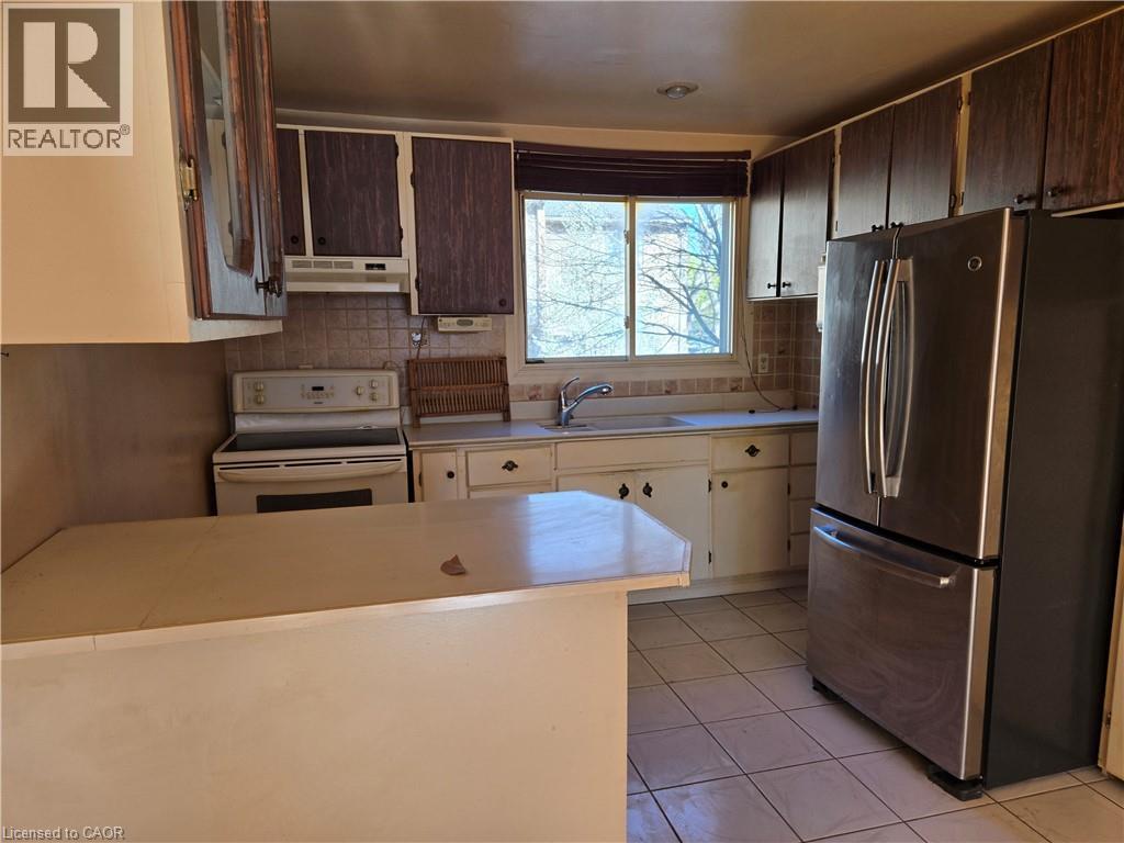 Kitchen featuring wood-look upper cabinetry, white lower cabinetry, and a white countertop - 95 Fonthill Road Unit# 2, Hamilton, ON - Indoor Photo Showing Kitchen