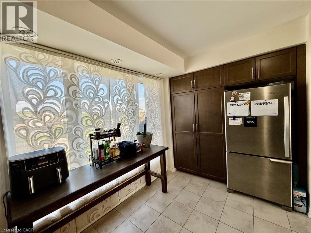 Kitchen area featuring wood-finish cabinetry, a stainless steel refrigerator, and tiled flooring - 146 Watson Parkway, Guelph, ON - Indoor