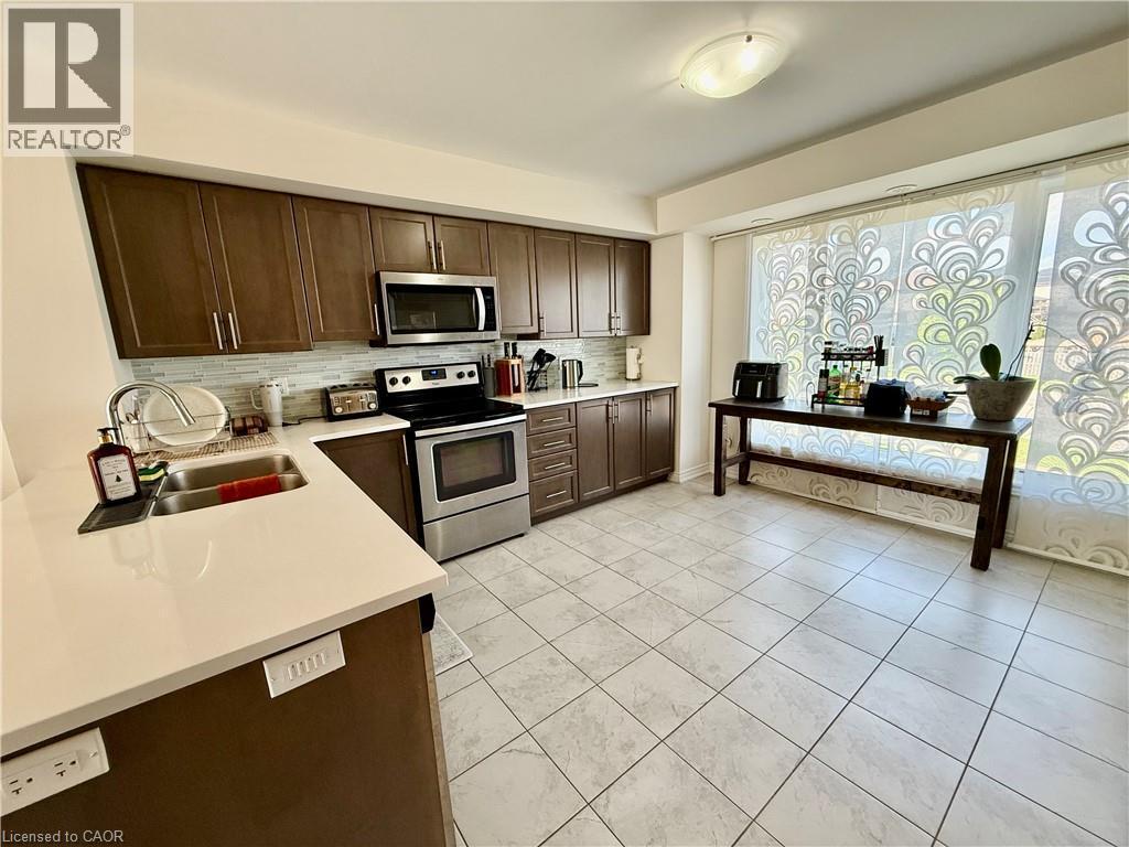 Kitchen featuring wood-finish cabinetry, stainless steel appliances, a double basin sink, and light-toned countertops - 146 Watson Parkway, Guelph, ON - Indoor Photo Showing Kitchen With Stainless Steel Kitchen With Double Sink