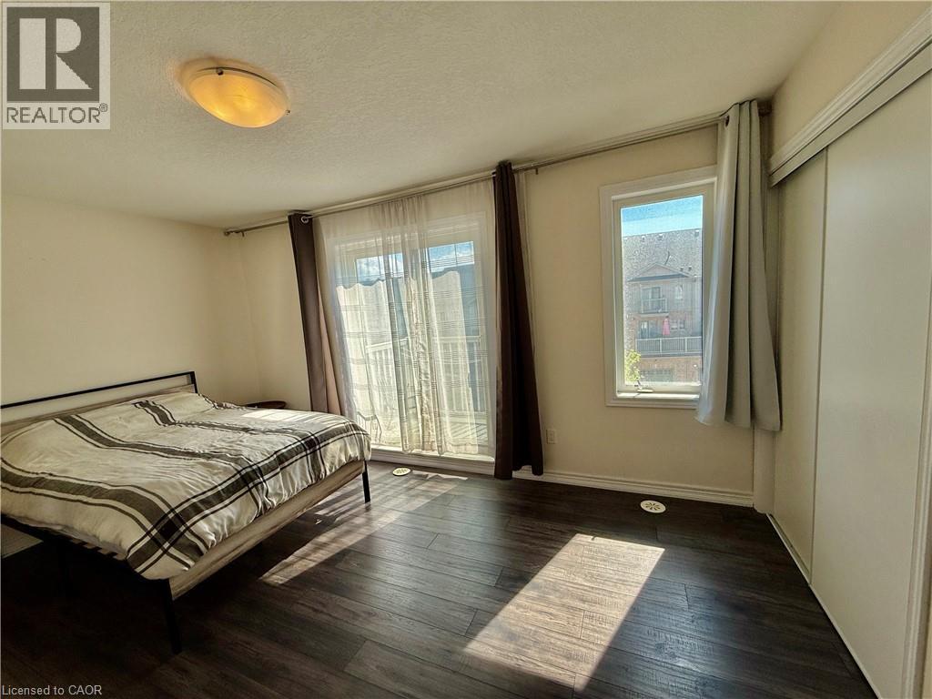 Bedroom featuring dark wood-finish flooring, white walls, and a sliding glass door to a balcony - 146 Watson Parkway, Guelph, ON - Indoor Photo Showing Bedroom