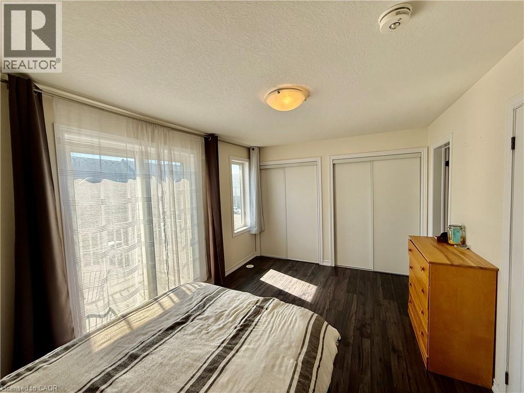 Bedroom featuring wood-finish flooring, a ceiling-mounted light fixture, and two sliding door closets - 146 Watson Parkway, Guelph, ON - Indoor Photo Showing Bedroom