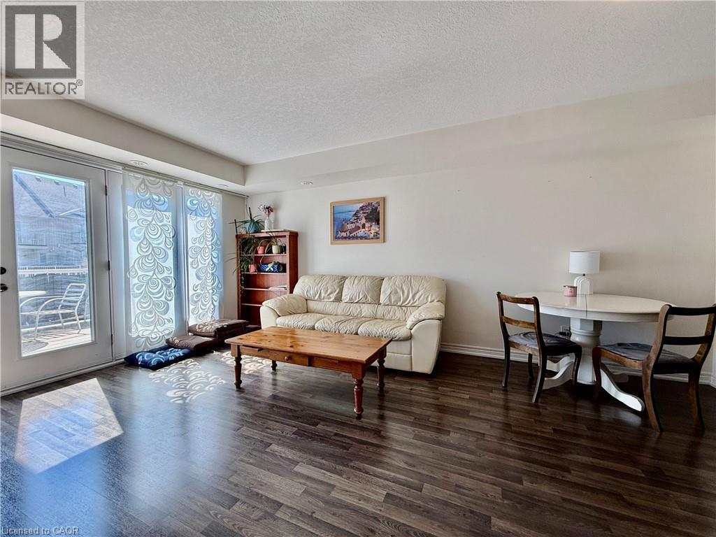 Living area featuring wood-finish flooring, light-toned walls, and a multi-panel glass door leading to an outdoor patio - 146 Watson Parkway, Guelph, ON - Indoor Photo Showing Living Room