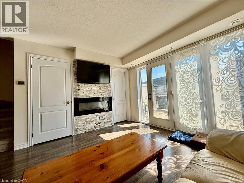 Living area featuring wood-finish flooring, a contemporary built-in fireplace with a stone-clad surround, and recessed ceiling lighting - 146 Watson Parkway, Guelph, ON - Indoor Photo Showing Living Room With Fireplace