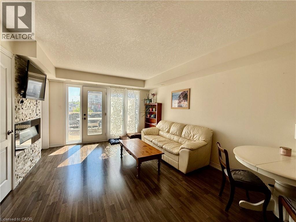 Living area featuring wood-finish flooring, a contemporary fireplace with a stacked stone facade, and double patio doors - 146 Watson Parkway, Guelph, ON - Indoor Photo Showing Living Room