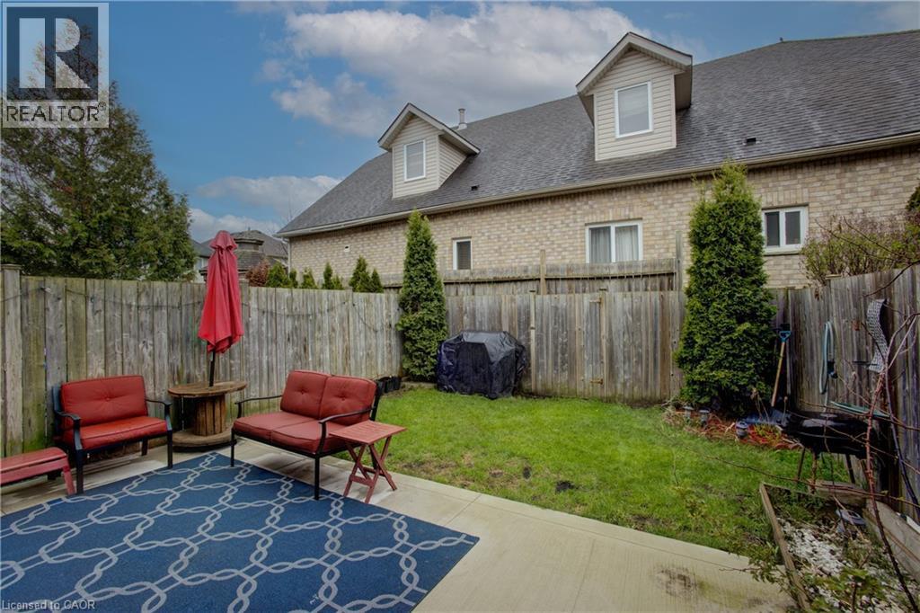 Private backyard featuring a concrete patio, wood fencing, and mature evergreen plantings - 53 Prosperity Drive, Kitchener, ON - Outdoor