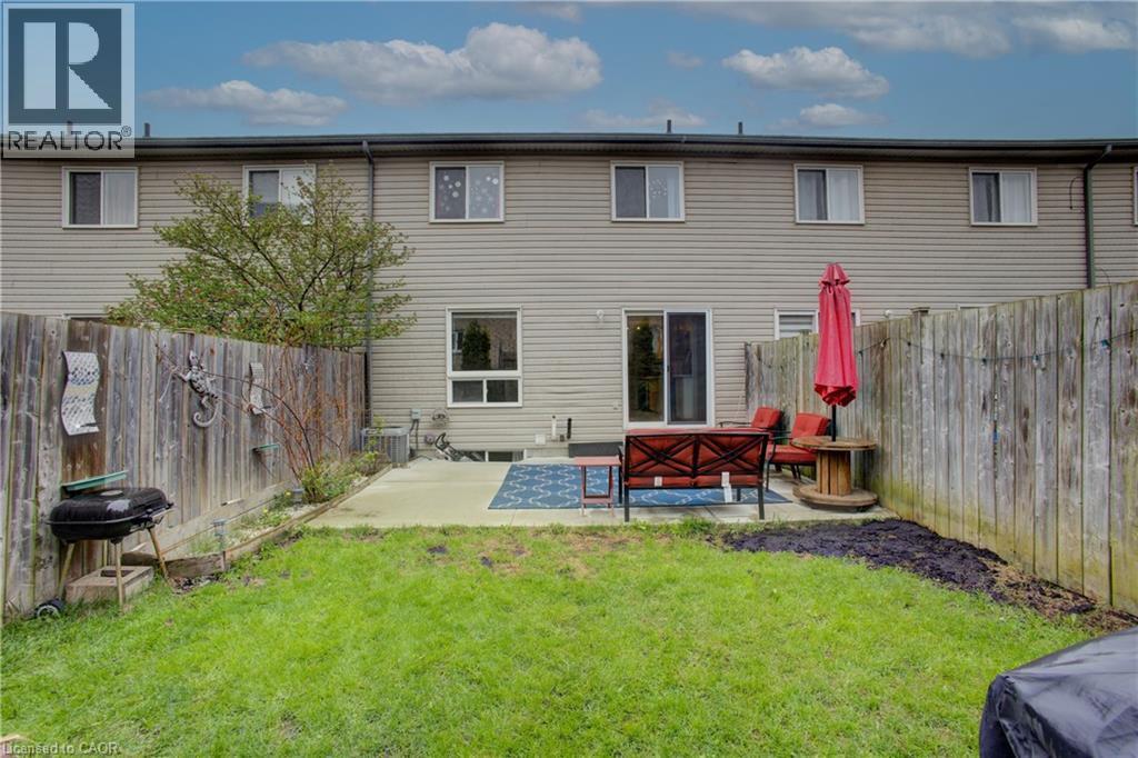 Private fenced backyard featuring a concrete patio, sliding glass door access, and a manicured lawn - 53 Prosperity Drive, Kitchener, ON - Outdoor With Exterior