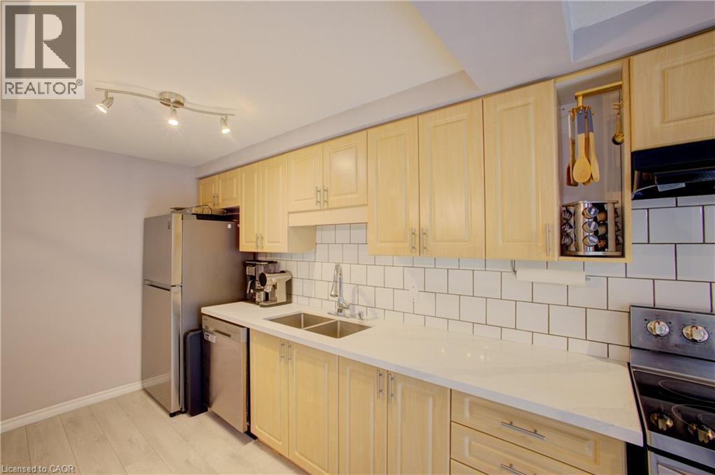 Kitchen featuring light wood cabinetry, a subway tile backsplash, light-toned countertops, and stainless steel appliances - 53 Prosperity Drive, Kitchener, ON - Indoor Photo Showing Kitchen With Double Sink