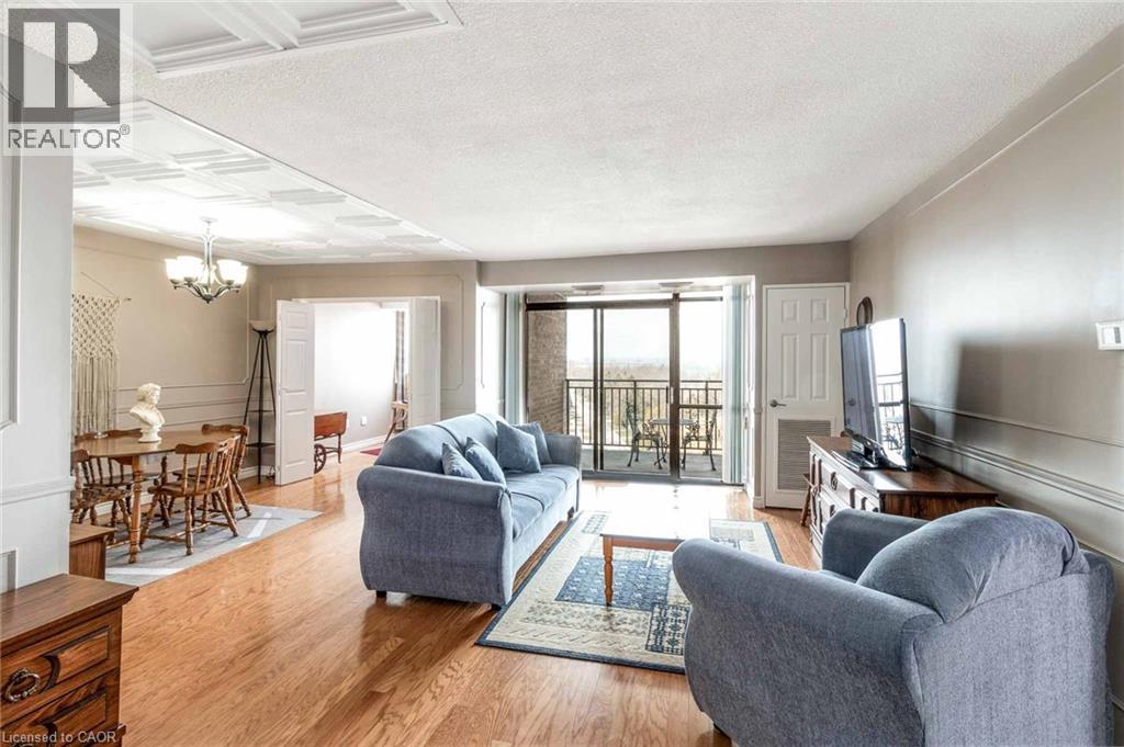 Open-concept living space featuring wood-finish flooring, a tray ceiling in the dining area, and a sliding glass door to an outdoor balcony - 500 Green Road Unit# 901, Stoney Creek, ON - Indoor Photo Showing Living Room
