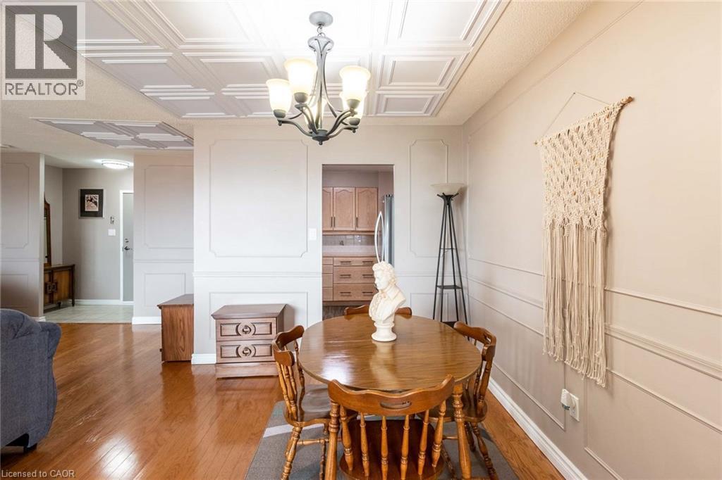 Dining area featuring a decorative ceiling, wood-finish flooring, and wainscoting details on the walls - 500 Green Road Unit# 901, Stoney Creek, ON - Indoor Photo Showing Dining Room