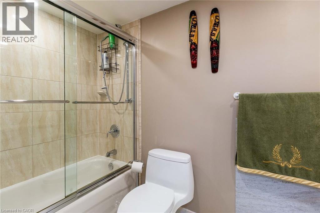 Bathroom featuring a white tub, chrome fixtures, and a tiled shower surround with glass sliding doors - 500 Green Road Unit# 901, Stoney Creek, ON - Indoor Photo Showing Bathroom